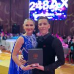 Dance couple with an award. The lady is in a blue ballroom Dress.